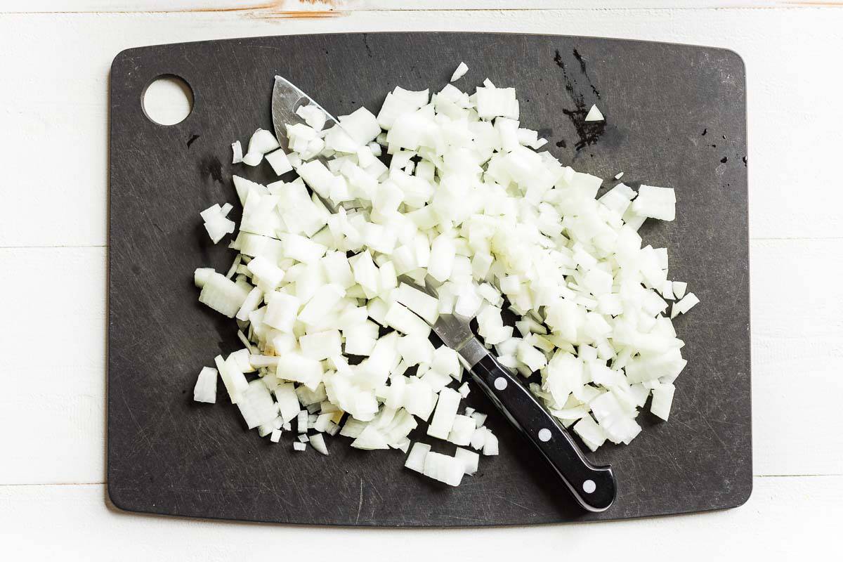 Diced up white onion on a black cutting board.