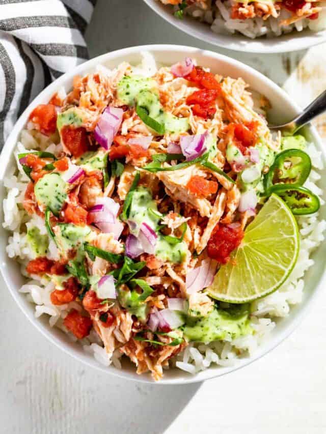 Two bowls filled with rice topped with salsa chicken, salsa, and cilantro lime dressing.