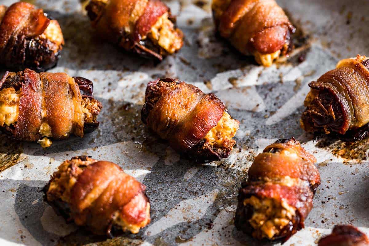 Finished bacon wrapped dates on white parchment paper.