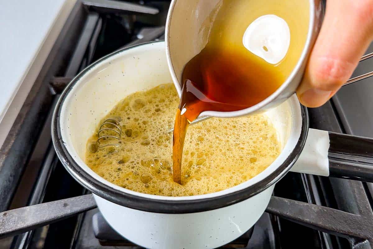 Pouring the maple syrup into the saucepan with the browned butter.