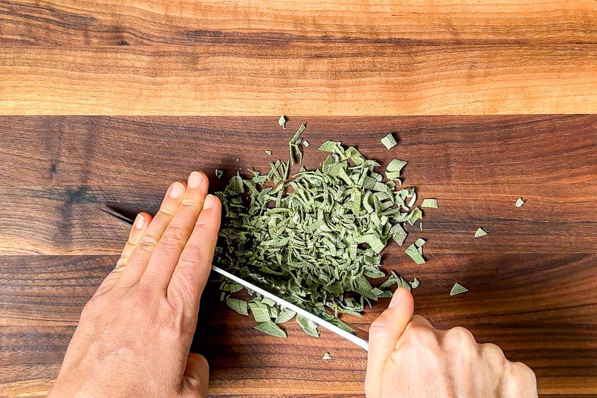 Chopping up the sage leaves on a wood cutting board.