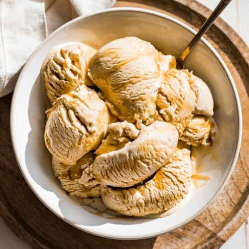Scoops of maple ice cream in a white bowl drizzled with maple syrup.