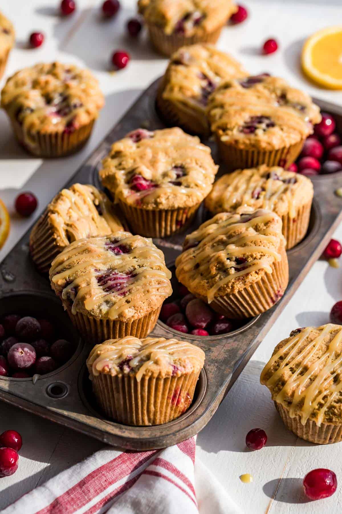 Cranberry Orange Muffins in an antique tin with muffins, orange slices, and cranberries around it.