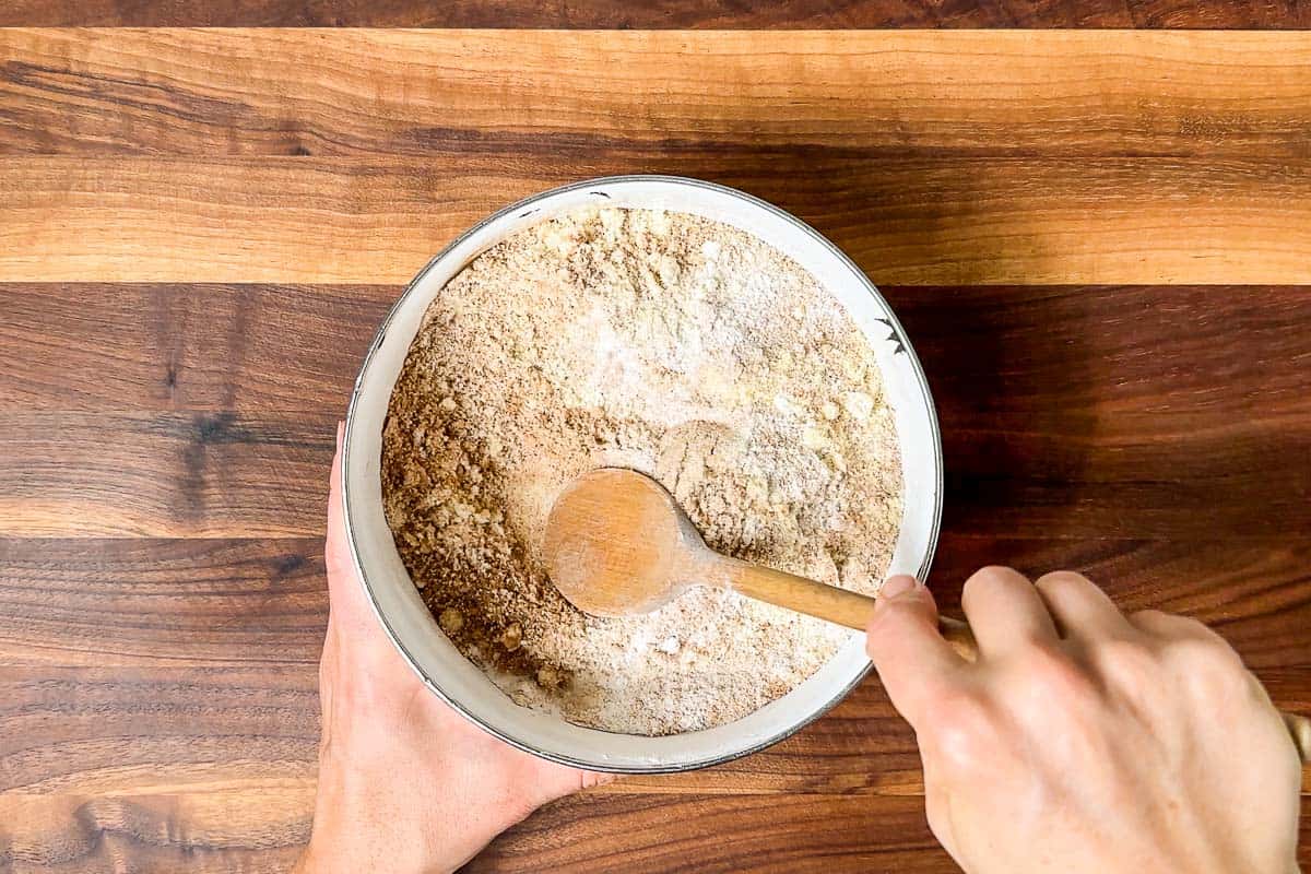 Mixing together the almond flour, tapioca starch, pumpkin spice, and cinnamon in a small bowl with a wood spoon.