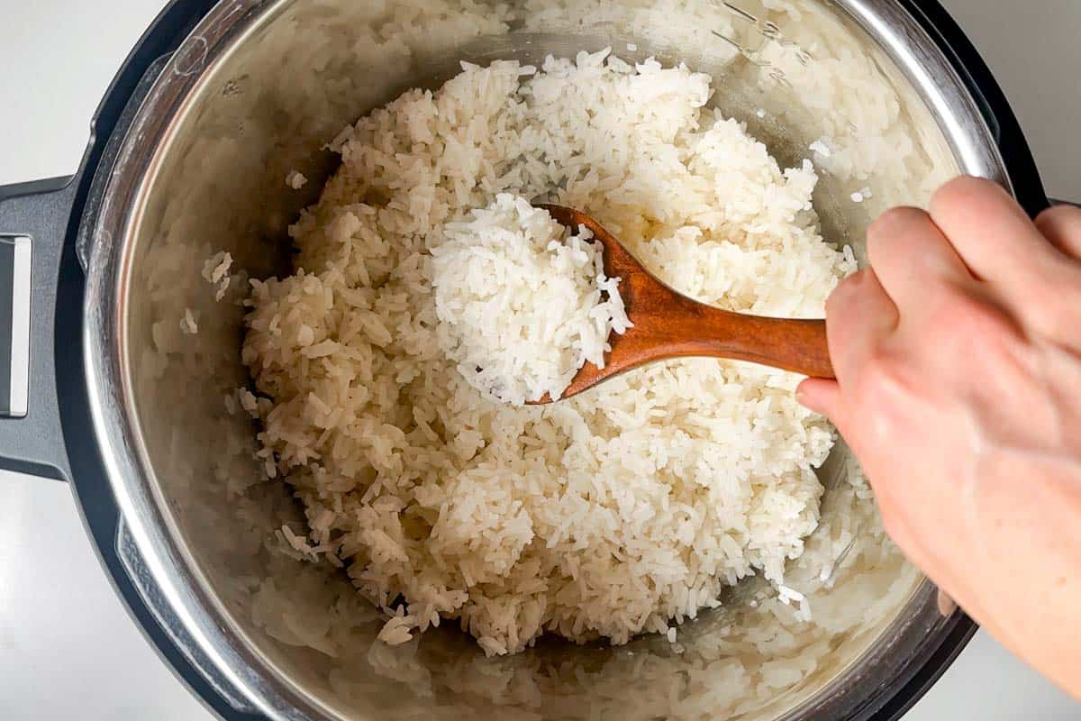 Fluffing up the cooked rice with a wood spoon after it's been cooked.