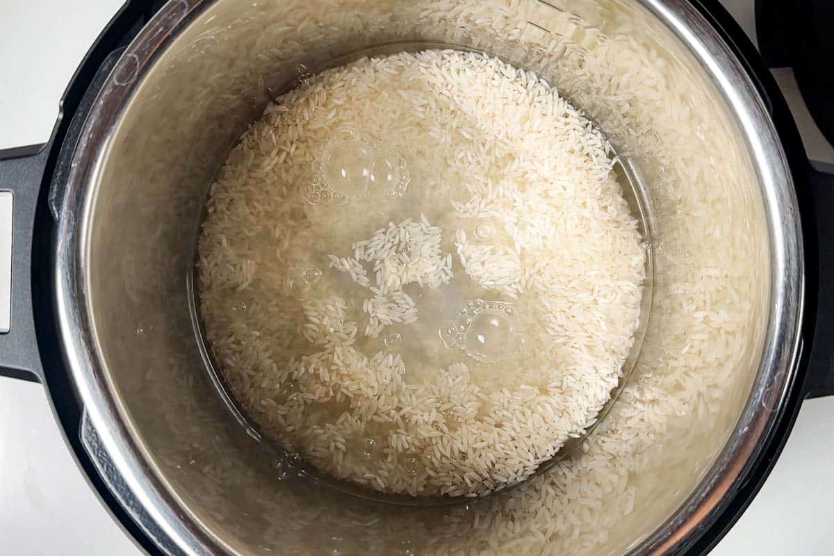 Adding long grain rice and water to an Instant Pot.