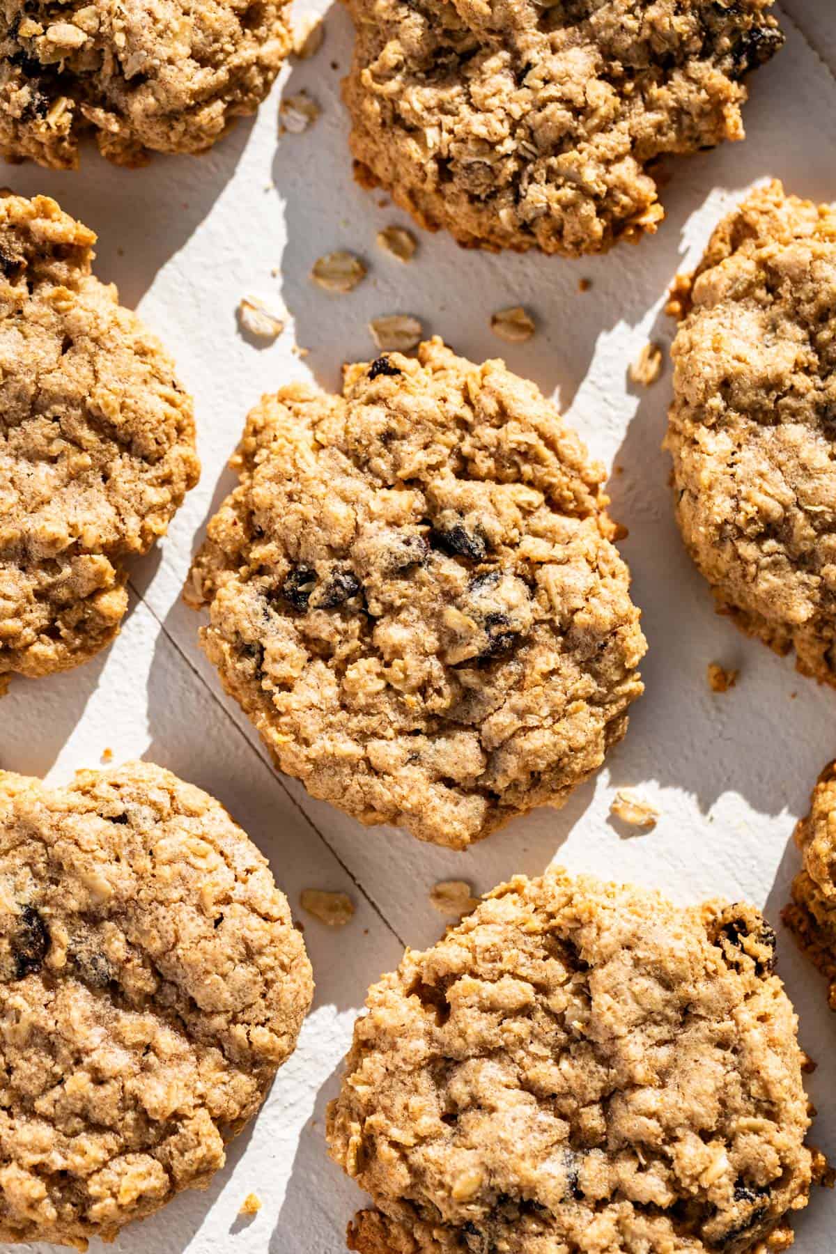 Oat Flour Oatmeal Raisin Cookies on a white board with cookie crumbs around them.