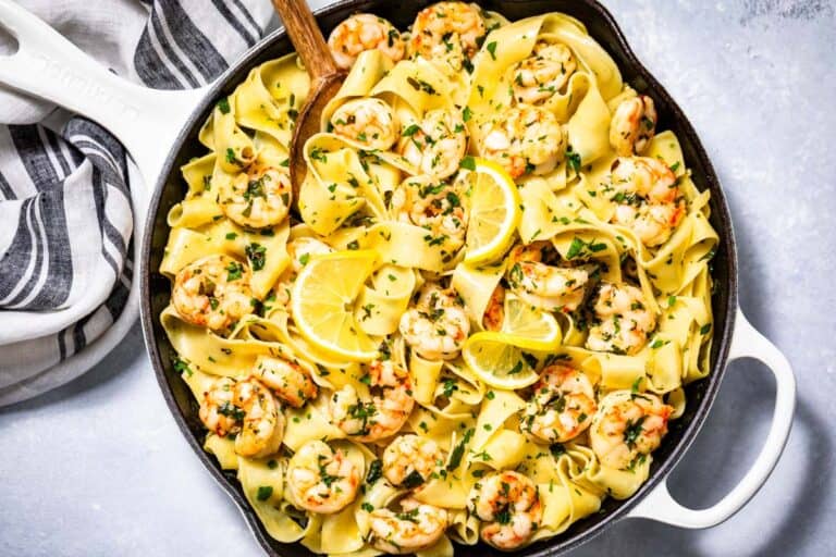Finished garlic butter shrimp pasta topped with lemon slices and chopped parsley in a large white skillet.