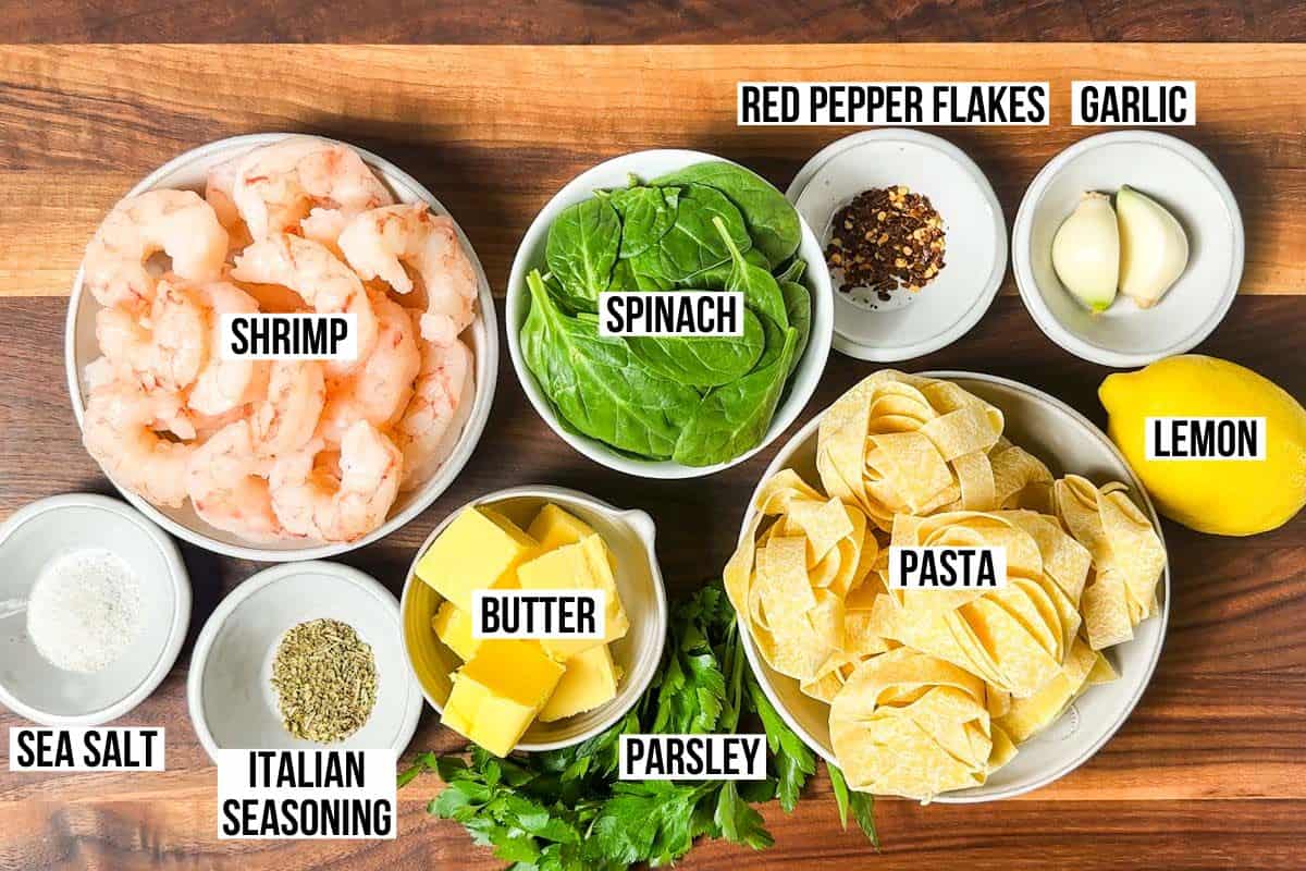Pappardelle pasta, shrimp, lemon, butter, garlic, and spices on a wooden cutting board.