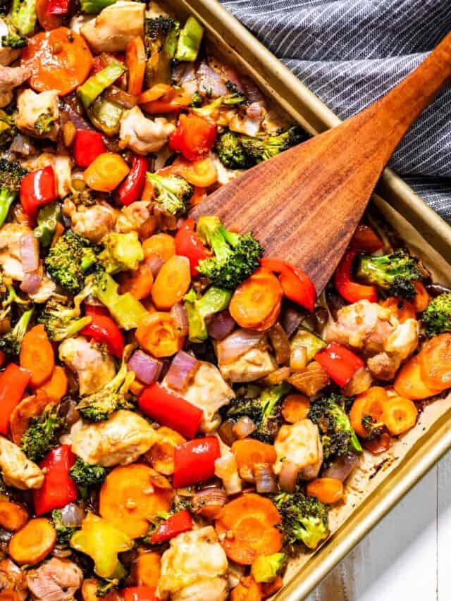 Sheet pan stir fry with a wood spatula scooping up some stir fry.
