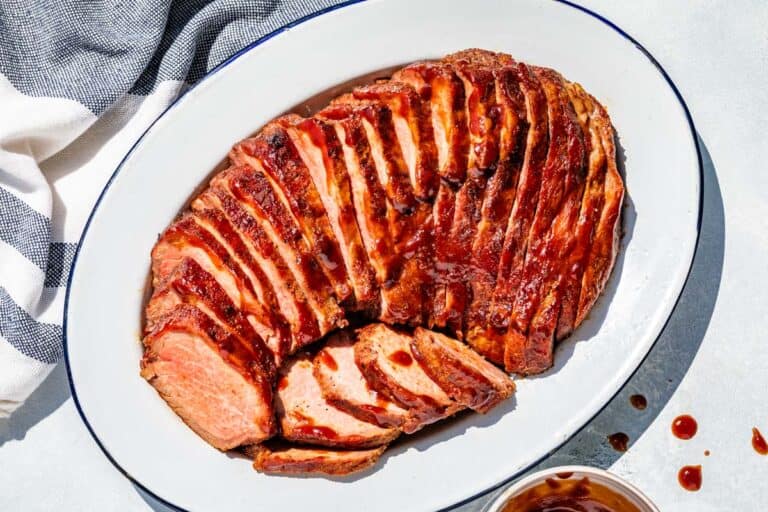 Sliced BBQ Smoked Tri Tip on a blue rimmed white oval platter.