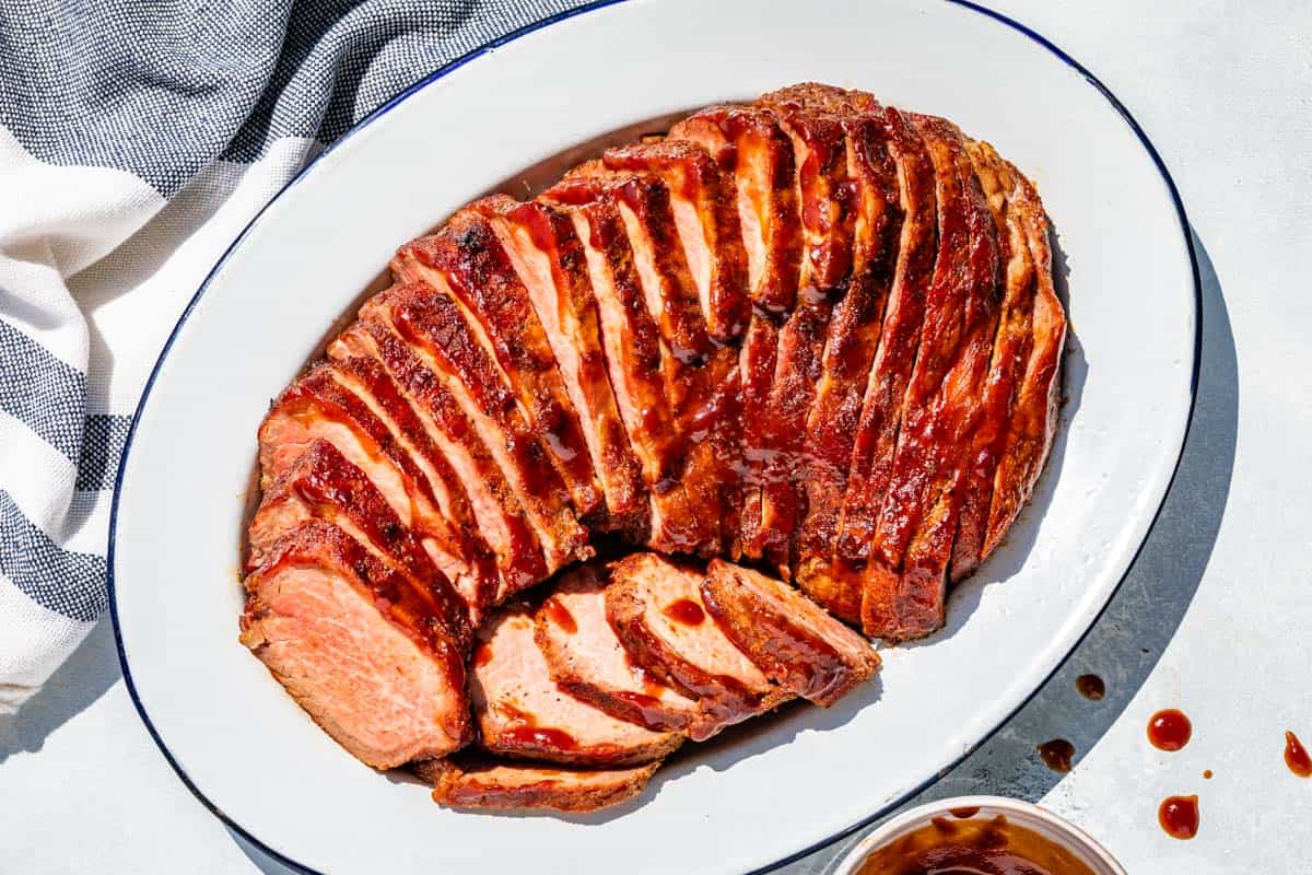 Sliced BBQ Smoked Tri Tip on a blue rimmed white oval platter.