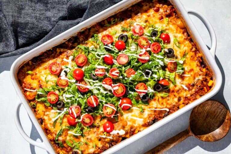 Finished Taco Casserole in a white baking dish with a wood serving spoon on the side.