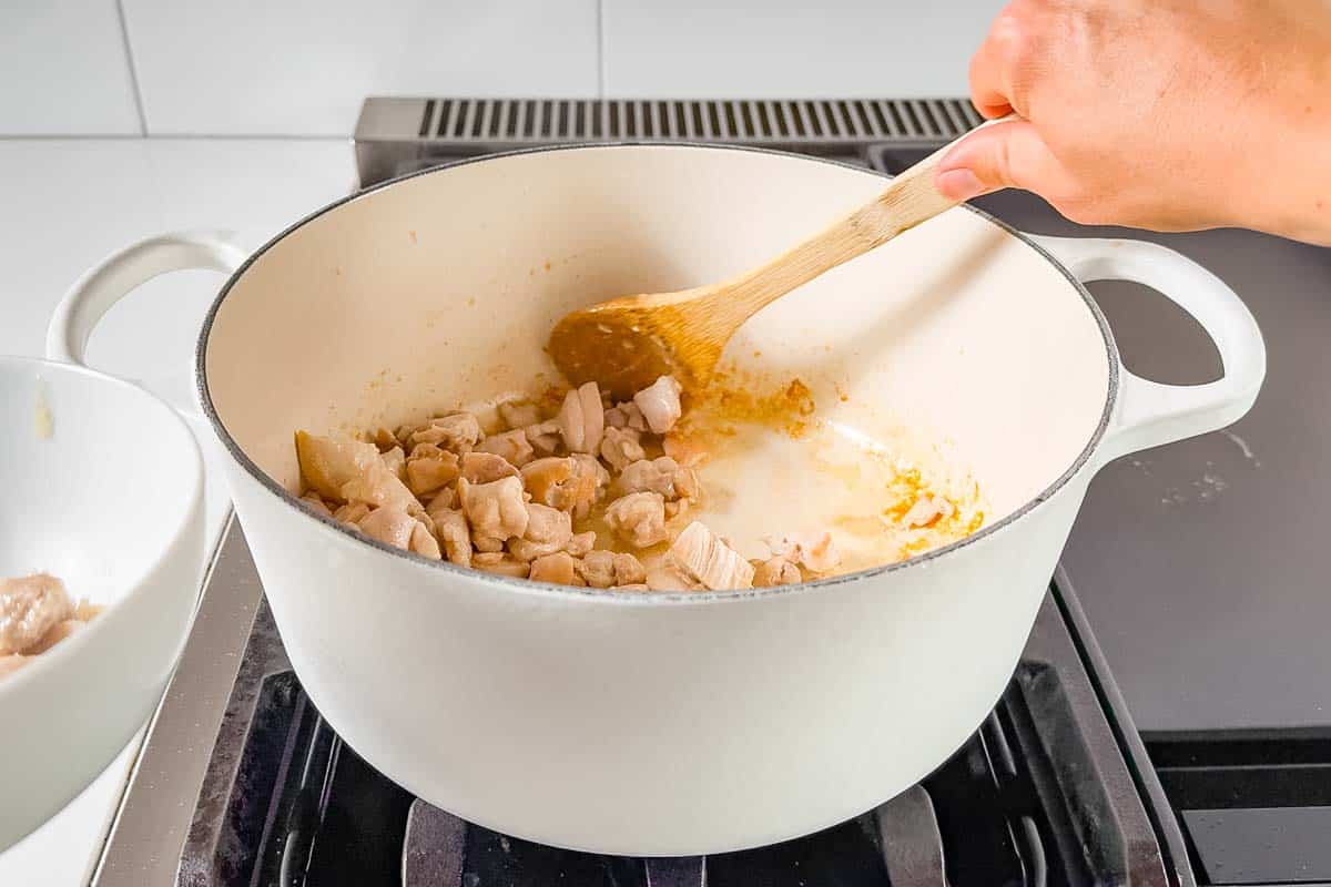 Sautéing cubed chicken in a dutch oven on the stove top.