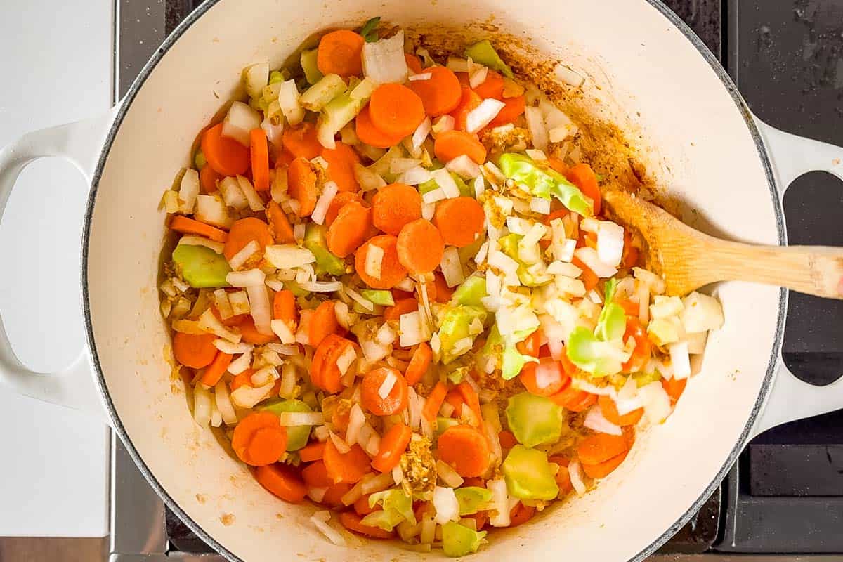 Adding the onions, carrots, and broccoli stems to the pan with the garlic and ginger.