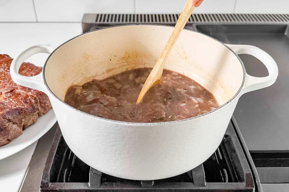 Adding the rosemary, thyme, beef broth, and red wine to the onion mixture.
