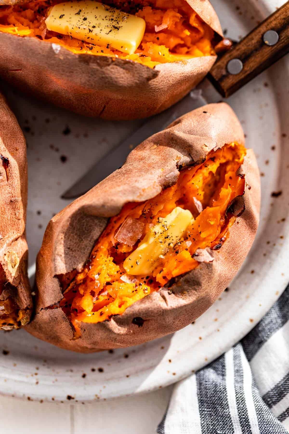 Baked sweet potatoes split open with butter and sea salt in them.