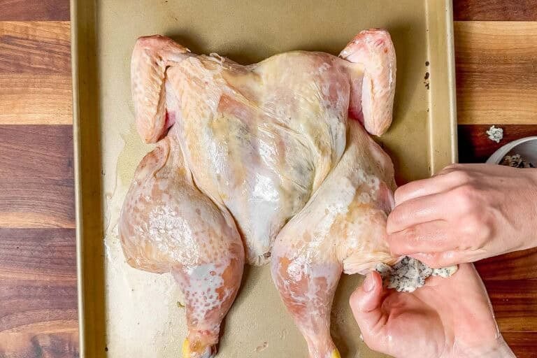 Putting herb butter under the skin of the spatchcocked chicken.