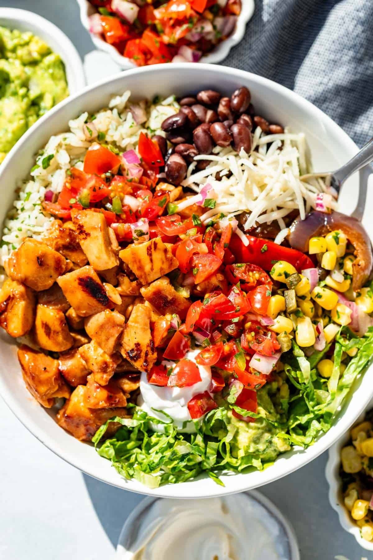 Chopped chipotle honey chicken made into a burrito bowl with cheese, black beans, cilantro lime rice, chili corn salsa, Pico de Gallo and sour cream.