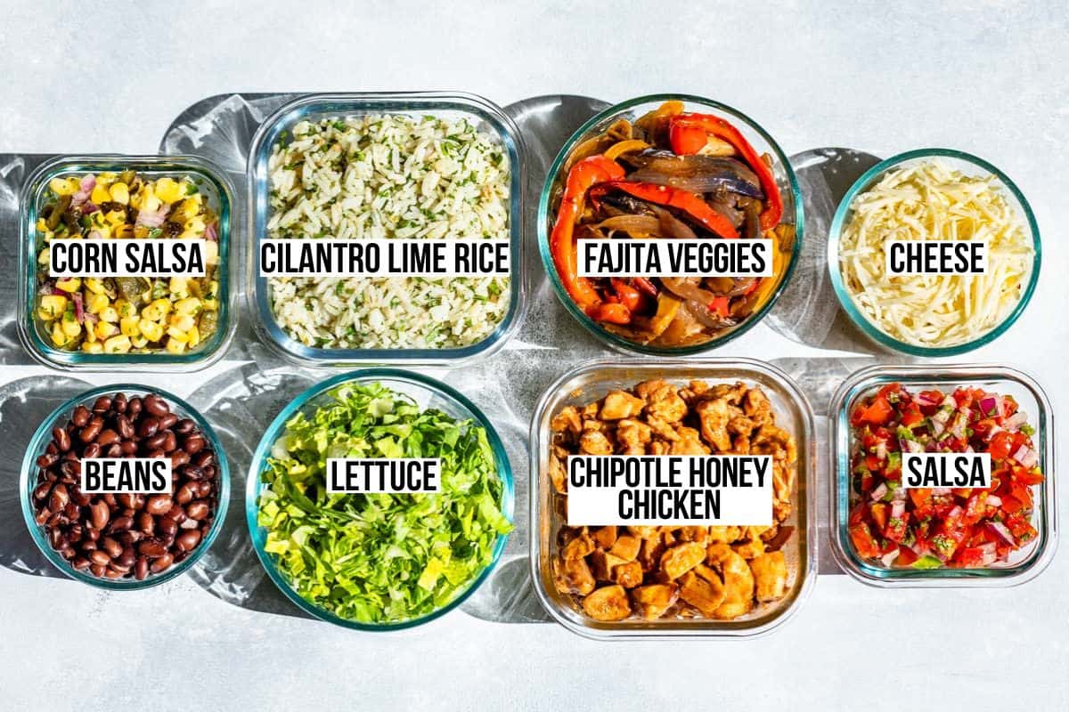 Glass containers of chipotle honey chicken, cilantro lime rice, black beans, fajita veggies, corn salsa, pico de gallo, cheese, and shredded lettuce.