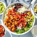 Chopped Chipotle Honey Chicken over a bed of rice, romaine, and black beans with cheese, corn salsa, and Pico de Gallo with bowls of salsa, sour cream, guacamole and more cheese on the side.