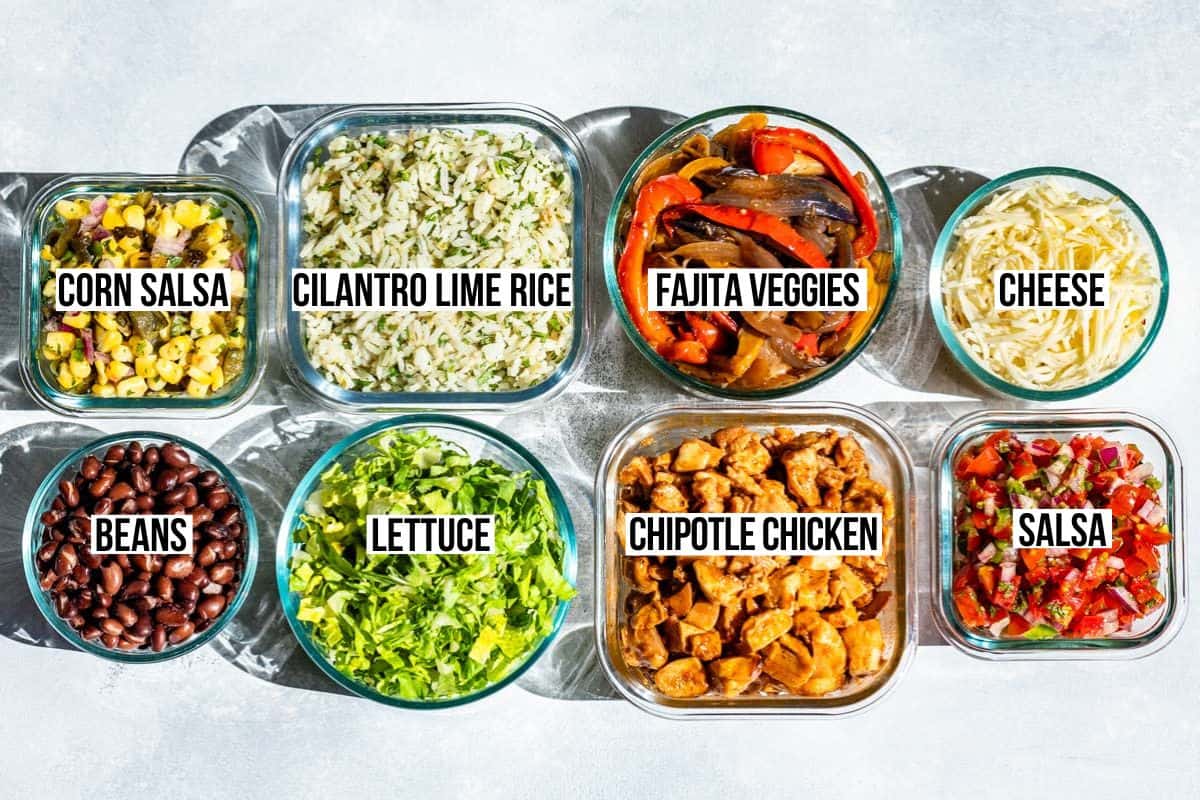 Glass containers of cilantro lime rice, black beans, fajita veggies, corn salsa, pico de gallo, cheese, and shredded lettuce.