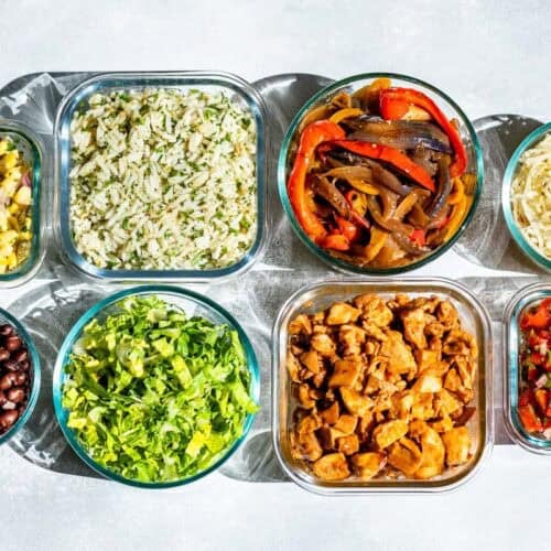 Glass containers of black beans, corn salsa, romaine lettuce, Cilantro Lime Rice, Fajita veggies, chipotle chicken, salsa, and cheese.