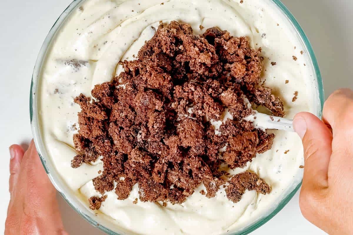 Mixing chocolate cookies into the vanilla ice cream base.