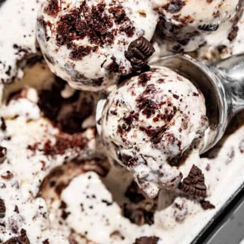 Three scoops of cookies and cream ice cream with a metal ice cream scoop.