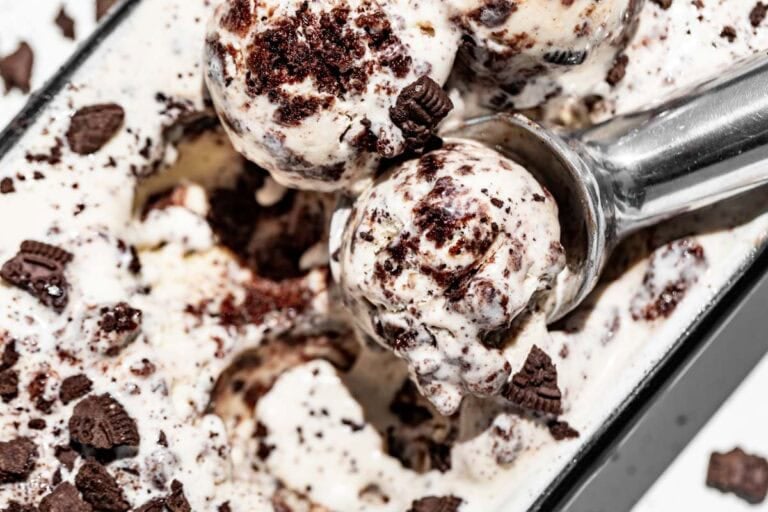 Three scoops of cookies and cream ice cream with a metal ice cream scoop.