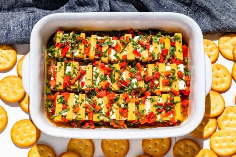 Marinated cheddar cheese and cream cheese in a small baking dish surrounded by crackers.