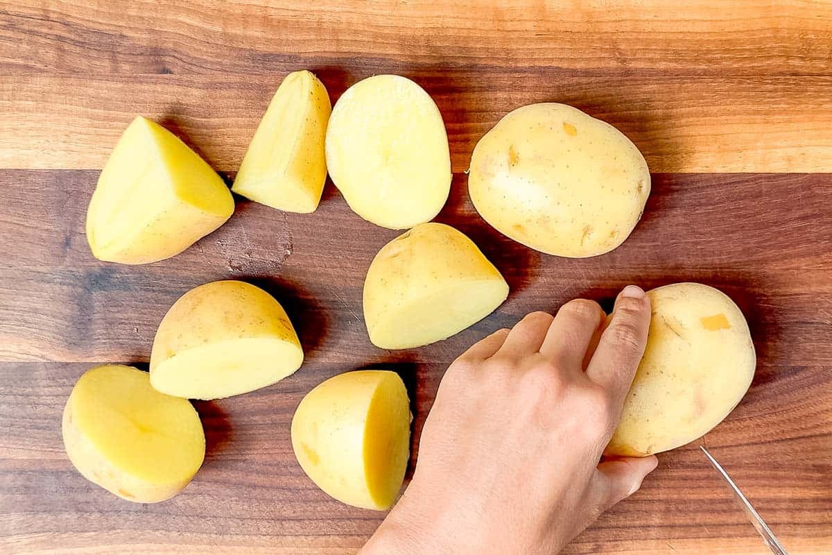 Cutting up Yukon gold potatoes on a wood cutting board.