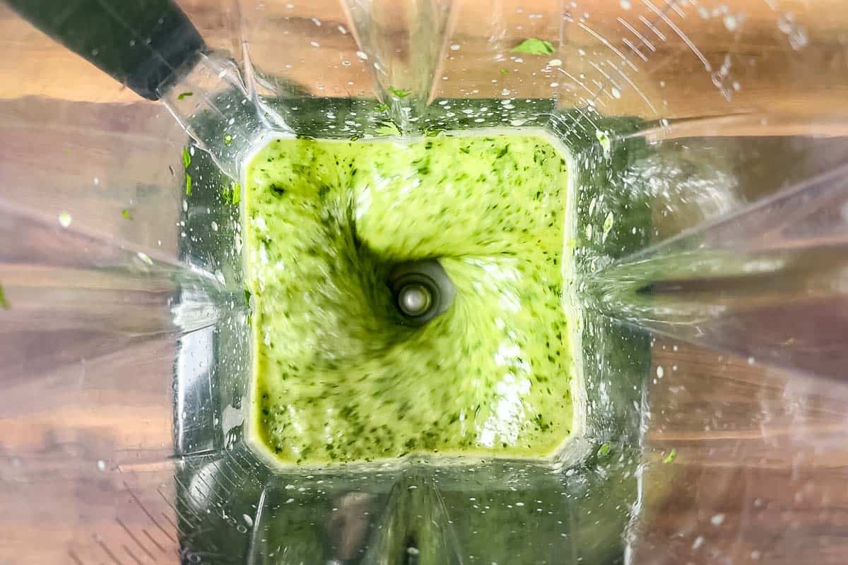 Blending the cilantro lime dressing in a blender container.