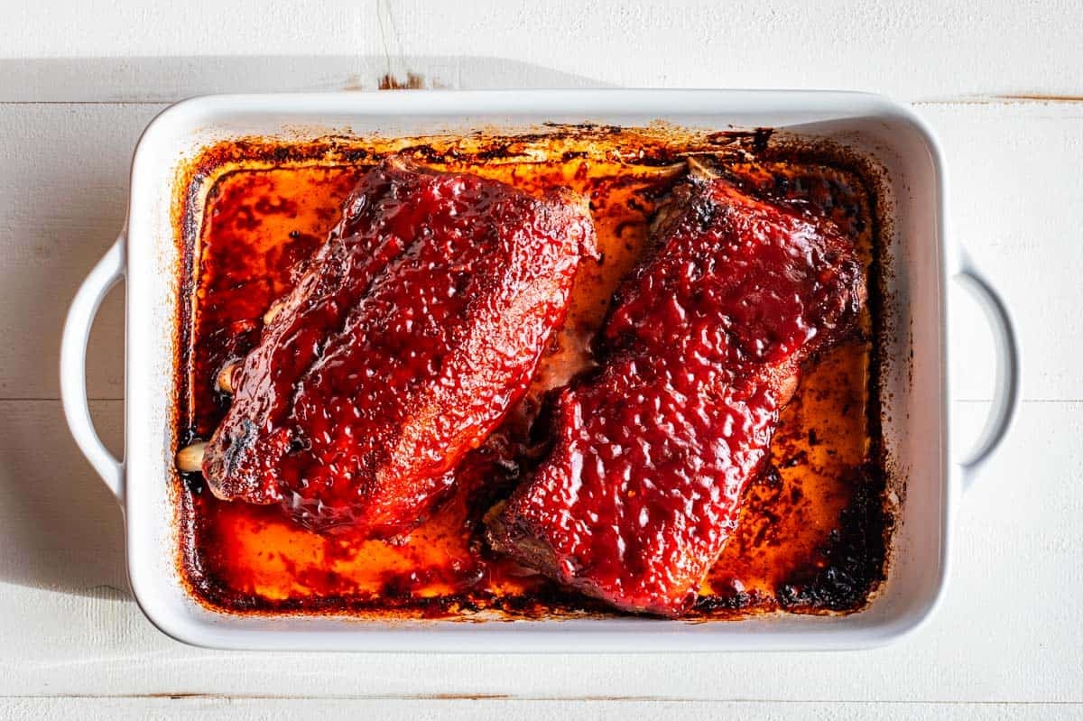 Finished ribs with the BBQ sauce broiled in a white baking dish.