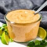 Chipotle Ranch in a clear glass jar with lime wedges and cilantro around it.