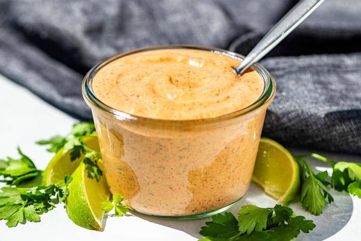 Chipotle Ranch in a clear glass jar with lime wedges and cilantro around it.