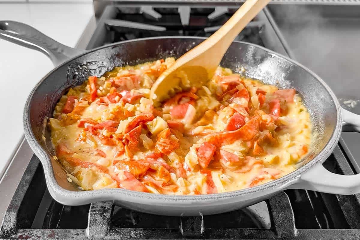 Simmering the roasted red pepper in the onion mixture with heavy cream.