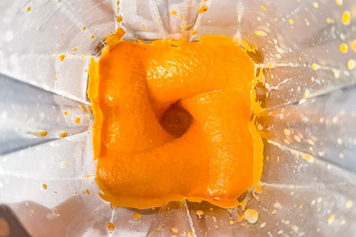 Blending the roasted red pepper sauce in a blender container.